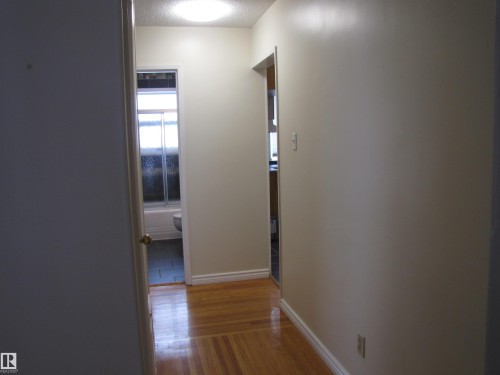 Hardwood-finish flooring throughout the hallway - 7135 87 Street, Edmonton, AB - Indoor Photo Showing Other Room
