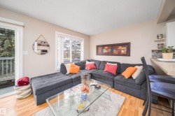 Open-concept living space featuring wood-finish flooring, a large window, and a sliding glass door to an outdoor deck - 