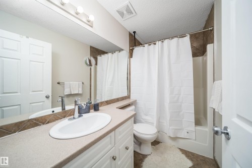 Bathroom featuring a white vanity with a light-toned countertop, an oval undermount sink, and chrome fixtures - 50 14603 Miller Boulevard, Edmonton, AB - Indoor Photo Showing Bathroom