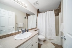Bathroom featuring a white vanity with a light-toned countertop, an oval undermount sink, and chrome fixtures - 