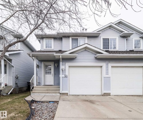 Two-story residence featuring light blue siding, a double garage with white doors, and a concrete driveway - 50 14603 Miller Boulevard, Edmonton, AB - Outdoor With Facade