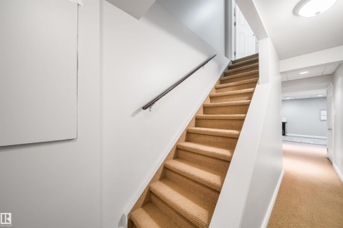 Carpeted staircase with a metal handrail - 50 14603 Miller Boulevard, Edmonton, AB - Indoor Photo Showing Other Room