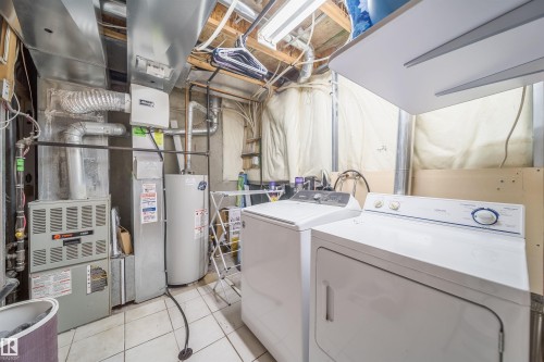 Dedicated utility space featuring a water heater, furnace, and laundry appliances - 50 14603 Miller Boulevard, Edmonton, AB - Indoor Photo Showing Laundry Room