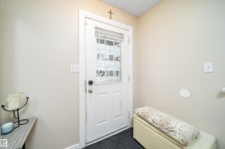 Entry door with decorative glass inserts, white trim, and a dark floor mat - 
