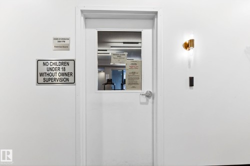White door with a window pane, featuring a brushed nickel handle and a wall-mounted sconce - 520 7463 May Common, Edmonton, AB -  Photo Showing Other Room