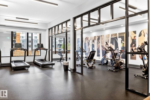 Fitness center featuring rubber flooring and floor-to-ceiling windows - 520 7463 May Common, Edmonton, AB - Indoor Photo Showing Gym Room