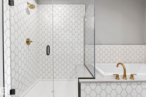 Shower and tub combination featuring white hexagonal tile, clear glass shower enclosure, and brushed brass fixtures - 520 7463 May Common, Edmonton, AB - Indoor Photo Showing Bathroom