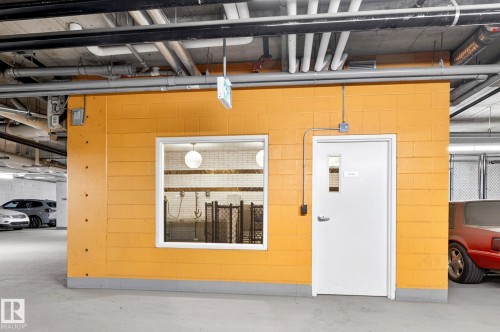 Utility room featuring a bright yellow brick exterior, a white entry door with a small window, and a large window providing visibility into the interior space - 520 7463 May Common, Edmonton, AB - Indoor Photo Showing Garage