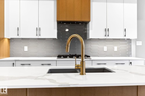 Kitchen featuring a gold-toned gooseneck faucet, undermount sink, and white countertops with subtle veining - 520 7463 May Common, Edmonton, AB - Indoor Photo Showing Kitchen With Upgraded Kitchen