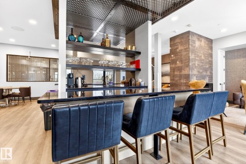 Expansive bar area featuring a polished dark countertop, built-in shelving, and recessed lighting - 520 7463 May Common, Edmonton, AB - Indoor Photo Showing Other Room