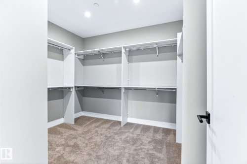 Walk-in closet featuring built-in shelving, hanging rods, recessed lighting, and carpeted flooring - 520 7463 May Common, Edmonton, AB - Indoor With Storage