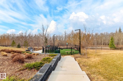 Fenced outdoor area featuring an artificial turf surface, a picnic table, and a black metal fence with two black light fixtures - 520 7463 May Common, Edmonton, AB - Outdoor With View