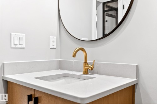 Integrated sink basin with a gold-tone faucet, set into a light-toned countertop with a matching backsplash - 520 7463 May Common, Edmonton, AB - Indoor Photo Showing Bathroom