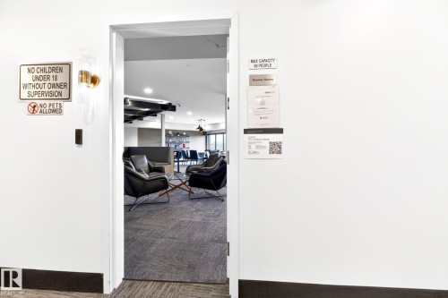 Open doorway leading to a carpeted room with multiple armchairs arranged around a coffee table - 520 7463 May Common, Edmonton, AB - 
