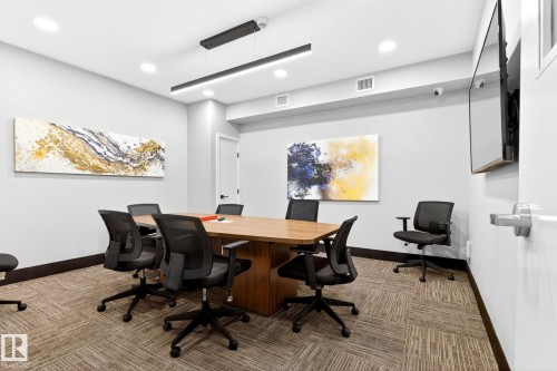 Conference room featuring a wood-finish table, recessed lighting, linear pendant lighting, mounted display, and carpet tile flooring - 520 7463 May Common, Edmonton, AB - Indoor Photo Showing Other Room