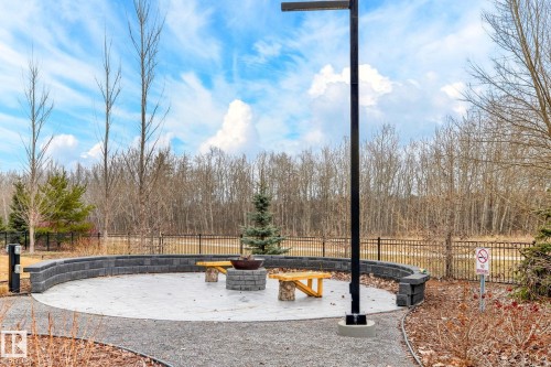 Circular paver patio featuring a built-in fire pit and a curved retaining wall - 520 7463 May Common, Edmonton, AB - Outdoor