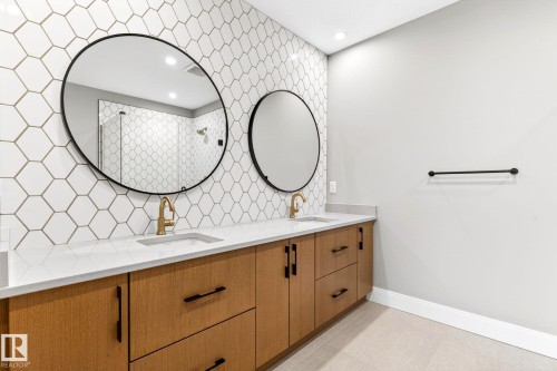 Bathroom featuring a dual vanity with wood-finish cabinetry, quartz countertops, and matte black hardware - 520 7463 May Common, Edmonton, AB - Indoor Photo Showing Bathroom