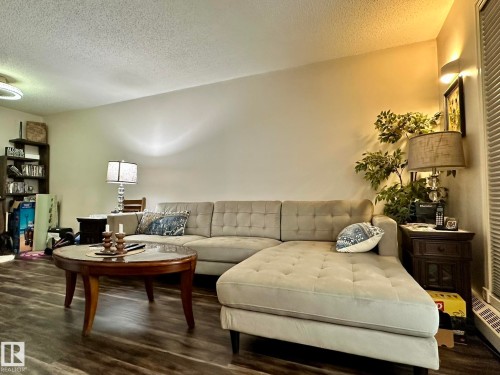Spacious living area featuring wood-finish flooring, a textured ceiling, and neutral wall tones - 211 9619 174 Street, Edmonton, AB - Indoor Photo Showing Living Room