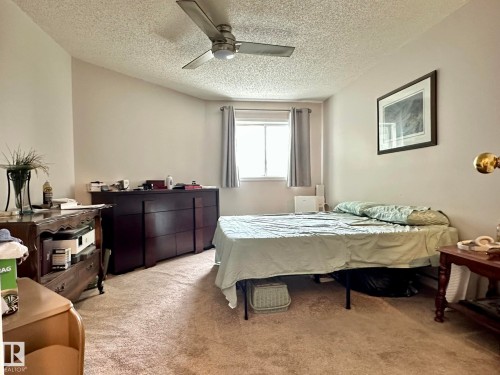 Wall-to-wall carpeting and a textured ceiling with a mounted ceiling fan - 211 9619 174 Street, Edmonton, AB - Indoor Photo Showing Bedroom