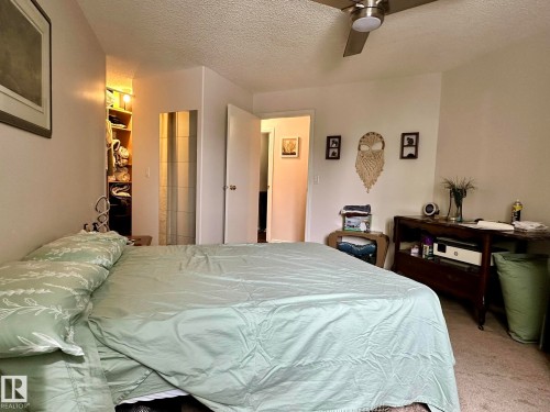 Carpeted bedroom featuring a ceiling fan, built-in shelving with lighting, and a neutral wall color - 211 9619 174 Street, Edmonton, AB - Indoor Photo Showing Bedroom
