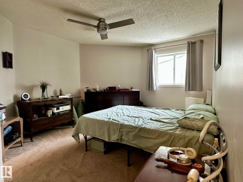 Carpeted bedroom featuring a ceiling fan with integrated lighting, a window with curtains, and neutral wall tones - 211 9619 174 Street, Edmonton, AB - Indoor Photo Showing Bedroom