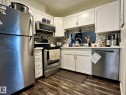 Kitchen featuring white cabinetry, stainless steel appliances, wood-finish flooring, and a mosaic tile backsplash - 211 9619 174 Street, Edmonton, AB  - Indoor Photo Showing Kitchen With Stainless Steel Kitchen 