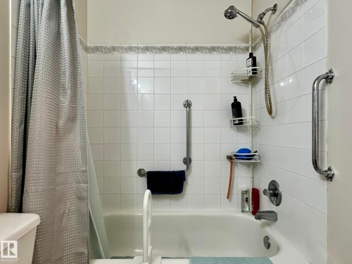 White subway tile shower surround with decorative accent border, chrome fixtures, and integrated grab bars - 211 9619 174 Street, Edmonton, AB - Indoor Photo Showing Bathroom