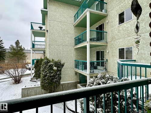 Multi-story building exterior featuring textured stucco siding and multiple private balconies with teal railings - 211 9619 174 Street, Edmonton, AB - Outdoor With Balcony With Exterior