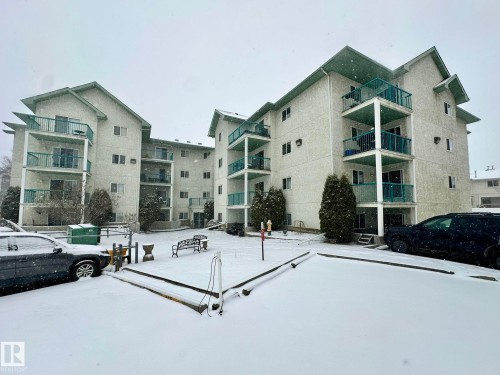 Multi-story building featuring light-colored stucco exterior and green-trimmed balconies - 211 9619 174 Street, Edmonton, AB - Outdoor With Balcony With Facade