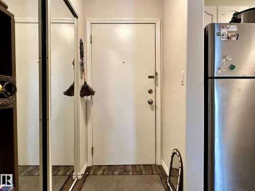 Entryway featuring wood-finish flooring and a full-length mirrored closet - 211 9619 174 Street, Edmonton, AB - Indoor Photo Showing Other Room