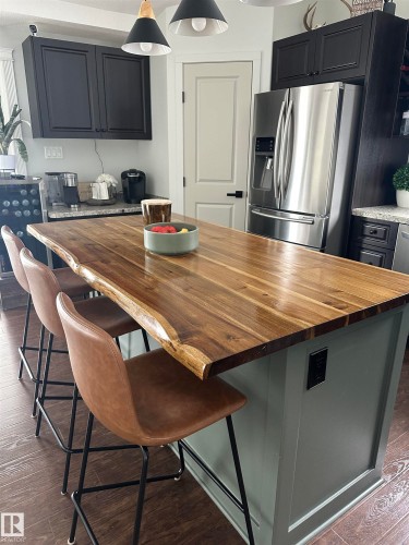 Custom kitchen island featuring a live-edge wood-finish countertop and painted paneling - 4926 58 Ave, Cold Lake, AB - Indoor