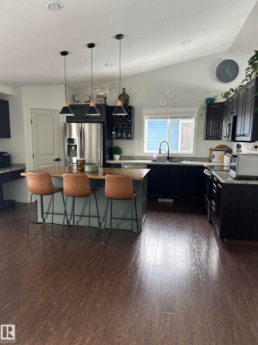 Spacious kitchen featuring dark cabinetry, light-toned countertops, and wood-finish flooring - 4926 58 Ave, Cold Lake, AB - Indoor Photo Showing Kitchen With Upgraded Kitchen