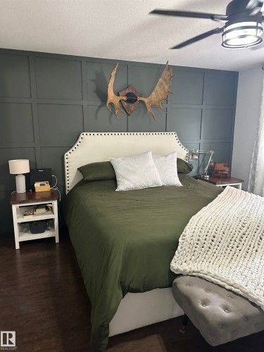 Accent wall featuring grid-style wainscoting and a ceiling fan with integrated lighting - 4926 58 Ave, Cold Lake, AB - Indoor Photo Showing Bedroom