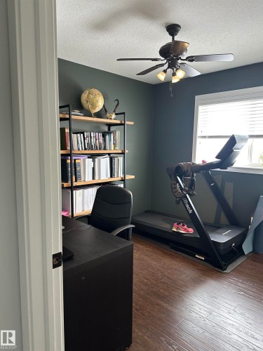 Interior room featuring dark wood-finish flooring and a ceiling fan with integrated lighting - 4926 58 Ave, Cold Lake, AB - Indoor Photo Showing Office