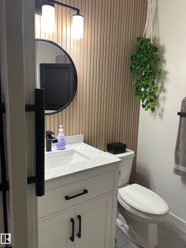 Bathroom featuring a white vanity with black hardware, a quartz countertop, and a rectangular undermount sink - 4926 58 Ave, Cold Lake, AB - Indoor Photo Showing Bathroom