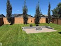 Expansive backyard featuring a paver patio with a built-in fire pit, surrounded by lush green lawn - 4926 58 Ave, Cold Lake, AB  - Outdoor With Backyard 