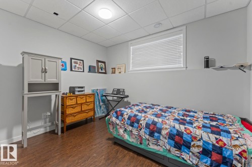 Room featuring wood-finish flooring, light grey walls, and a white acoustic tile ceiling with an overhead light fixture - 4926 58 Ave, Cold Lake, AB - Indoor Photo Showing Bedroom