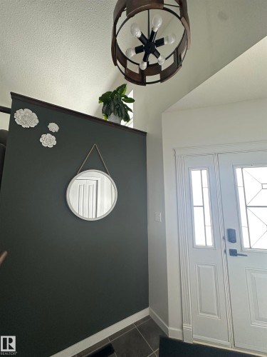 Entryway featuring a decorative round chandelier, double white paneled doors with integrated glass panels, and dark tile flooring - 4926 58 Ave, Cold Lake, AB - Indoor Photo Showing Other Room