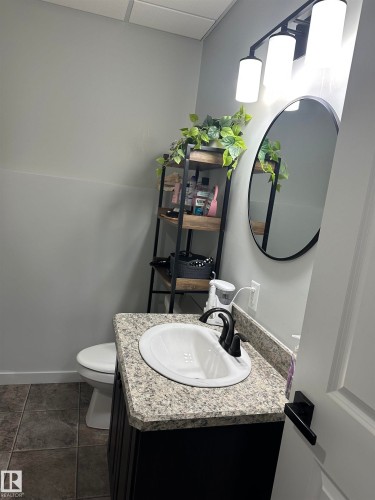 Bathroom featuring a granite-look countertop, undermount sink, and dark bronze faucet - 4926 58 Ave, Cold Lake, AB - Indoor Photo Showing Bathroom