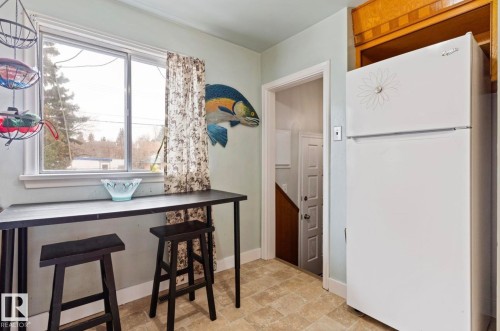 Kitchen space featuring a built-in refrigerator alcove and light-toned tile flooring - 7703 77 Avenue, Edmonton, AB 