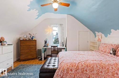 Sloped ceiling bedroom featuring a ceiling fan, wood-finish flooring, and a window with white trim - 7703 77 Avenue, Edmonton, AB 