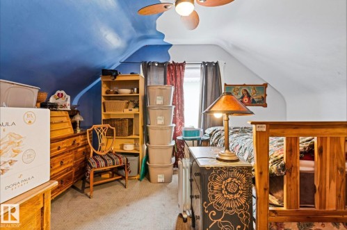 Attic space featuring a sloped ceiling, wood-finish ceiling fan, and carpeted flooring - 7703 77 Avenue, Edmonton, AB 