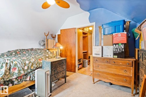 Carpeted room featuring a ceiling fan and a wood-finish door leading to an interior space - 7703 77 Avenue, Edmonton, AB 