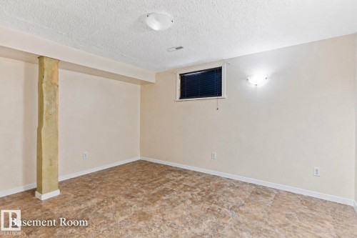 Basement room featuring neutral painted walls, patterned vinyl flooring, and a small window with blinds - 7703 77 Avenue, Edmonton, AB 