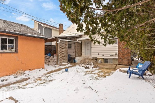 Rear exterior with white siding, red brick chimney, and a concrete patio - 7703 77 Avenue, Edmonton, AB 