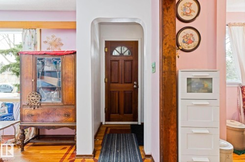 Arched entryway featuring a paneled wood door with an arched glass insert - 7703 77 Avenue, Edmonton, AB 