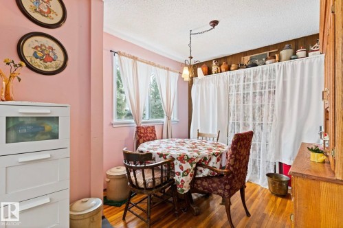 Dining area featuring hardwood flooring, a multi-pane window, and a wood-paneled accent wall - 7703 77 Avenue, Edmonton, AB 