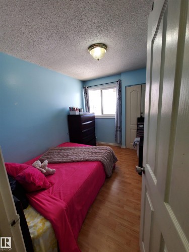 Room featuring wood-finish flooring, a window with drapery, a ceiling-mounted light fixture, and a built-in closet with a paneled door - 11814 157 Avenue, Edmonton, AB - Indoor Photo Showing Bedroom