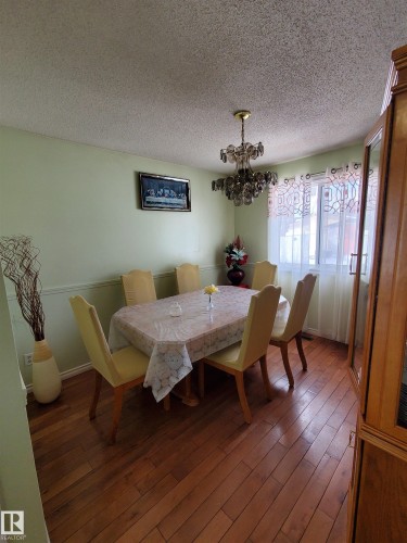 Formal dining space featuring wood-finish flooring, light green wall tones, and a decorative chandelier - 11814 157 Avenue, Edmonton, AB - Indoor Photo Showing Dining Room