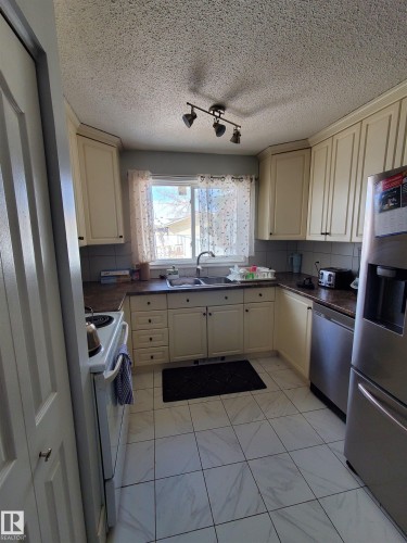 Kitchen featuring cream-colored cabinetry, laminate countertops, and a tile backsplash - 11814 157 Avenue, Edmonton, AB - Indoor Photo Showing Kitchen With Double Sink